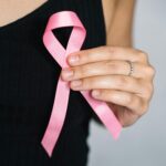 pexels photo 5482993 5482993 Close-up of a woman holding a pink ribbon for breast cancer awareness.